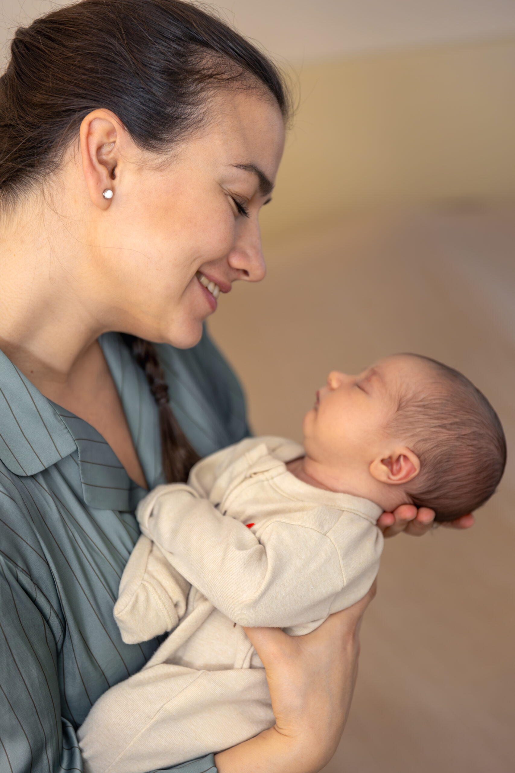 A young mother with a newborn baby. Newborn baby. High quality photo. Motherhood. Mother with baby at home. A mother holds a newborn baby in her arms.
